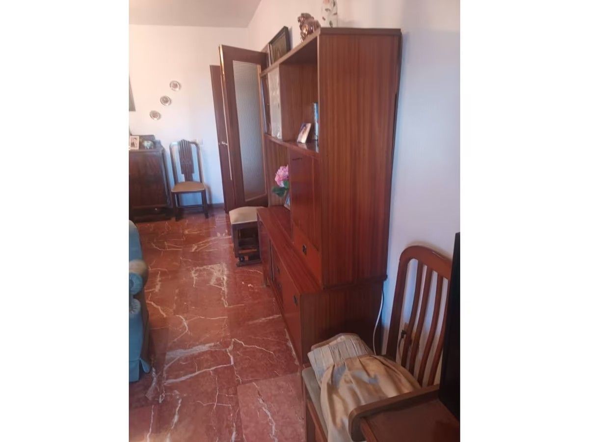 Una sala de estar con un sofá, sillas y una estantería.