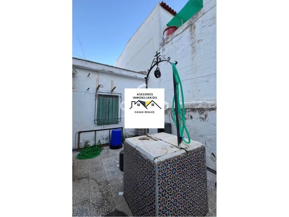 Un pozo con una manguera conectada a él está frente a un edificio.