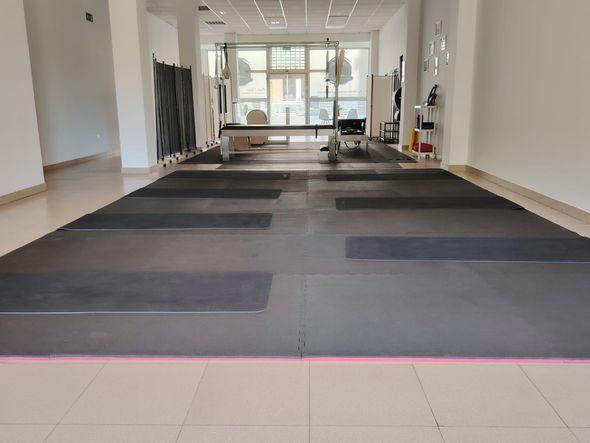 Una habitación grande con muchas colchonetas de yoga en el suelo.