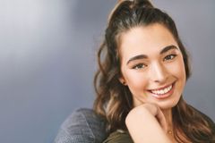 Un primer plano de una mujer sonriendo con la mano en la barbilla.