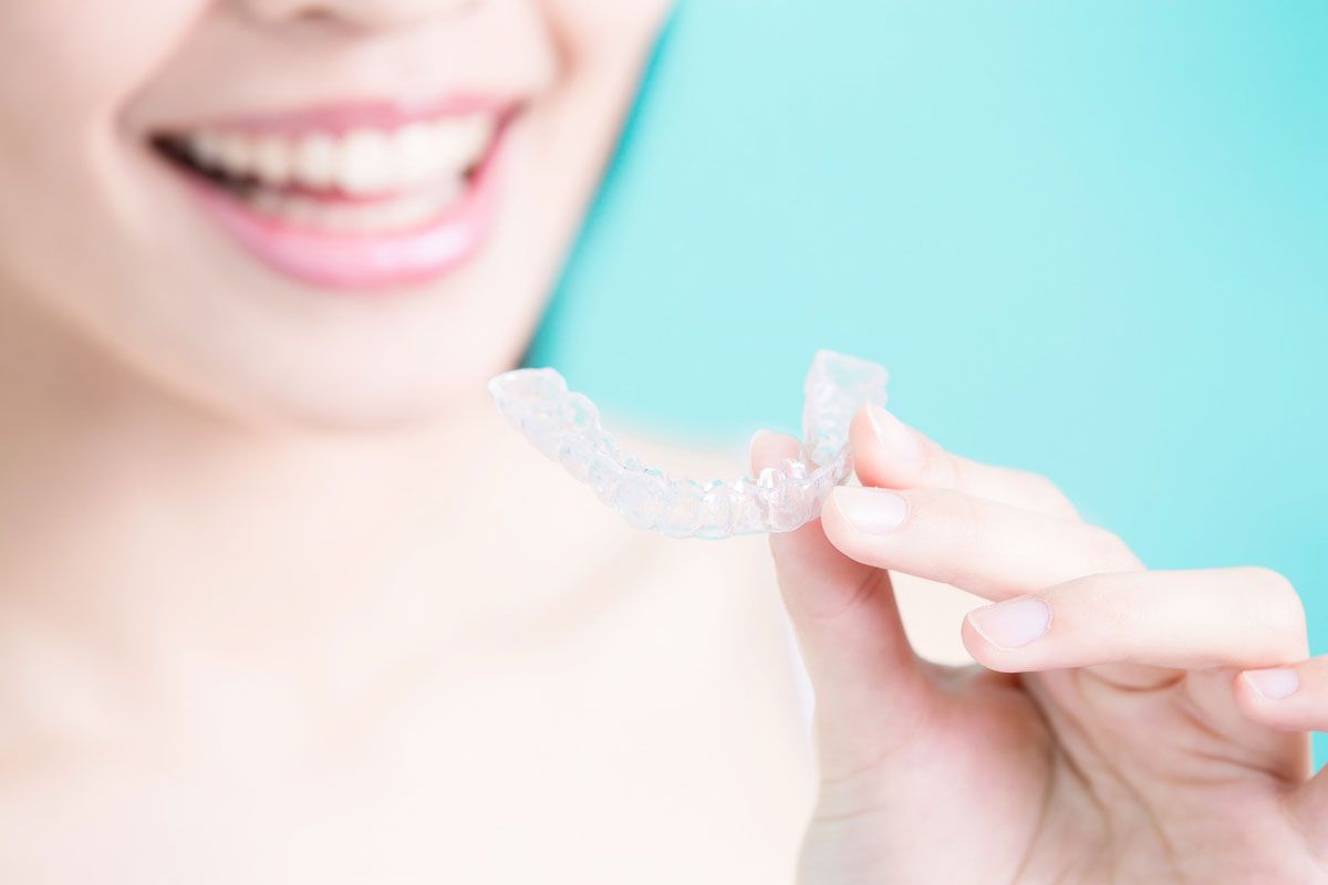Una mujer sostiene un aparato transparente delante de su boca.
