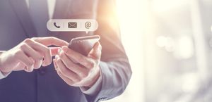 Personne en costume utilisant un smartphone, icônes pour téléphone, e-mail et localisation.