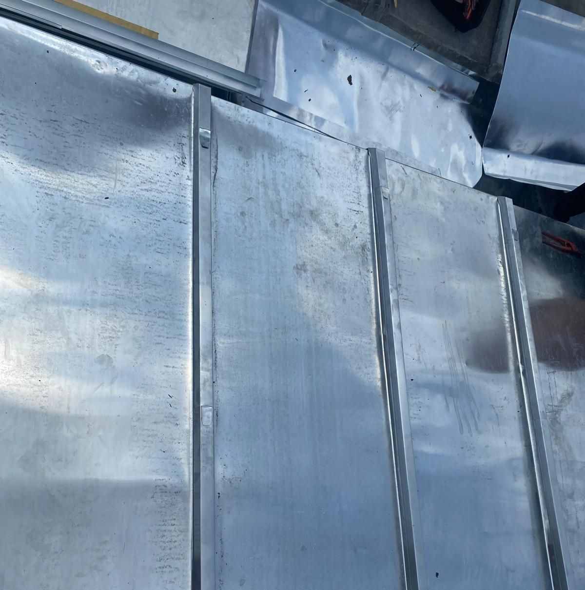 Gros plan sur des tôles ondulées, probablement un matériau de toiture, montrant les joints et quelques taches.