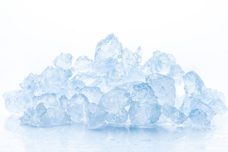 Montón de hielo picado, de distintos tonos de azul, sobre una superficie blanca.