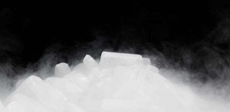 Niebla blanca o humo que se eleva desde lo que parece ser hielo sobre un fondo negro.