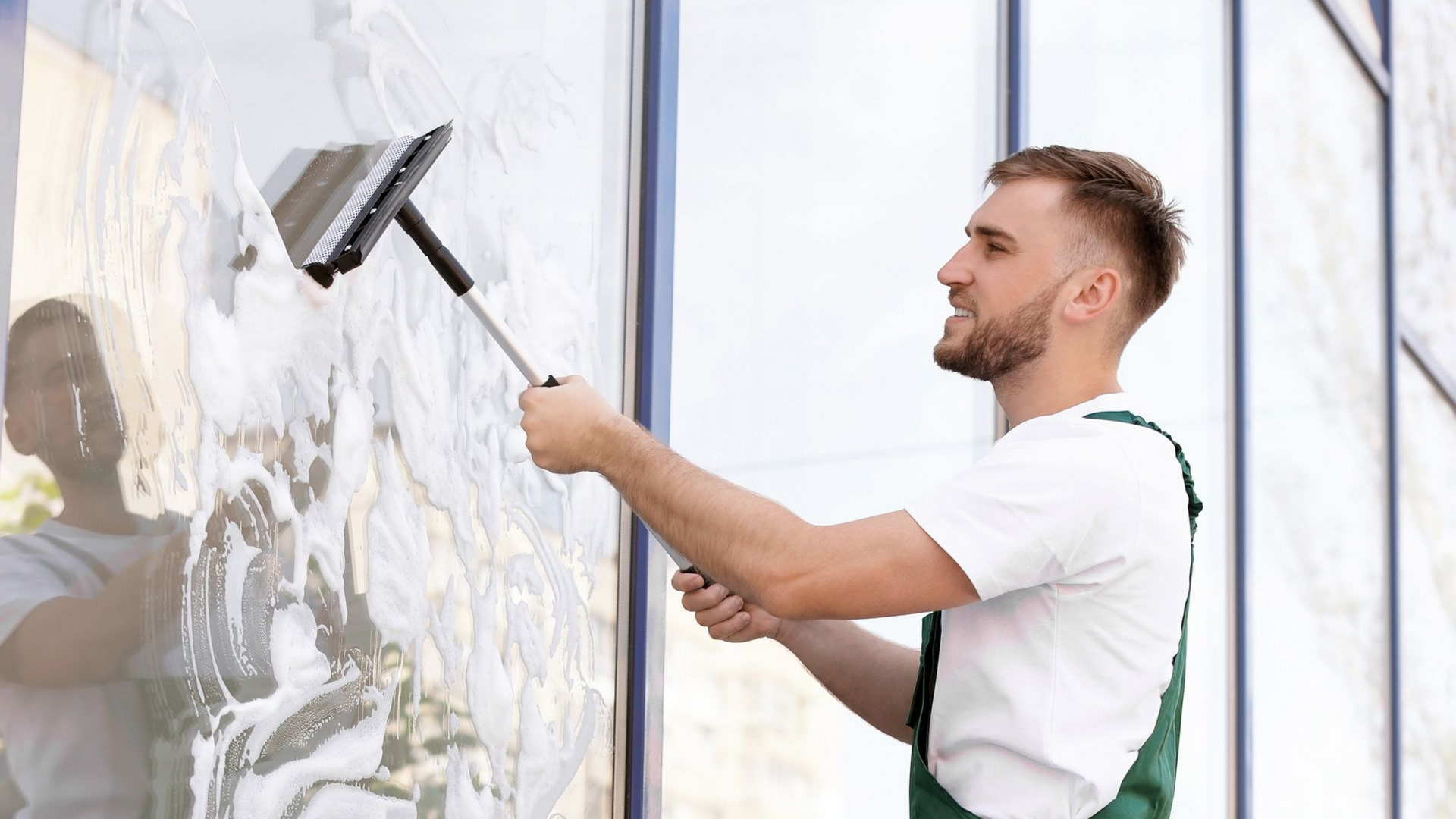 Technicien qui nettoie les vitrines d'un local professionnel.