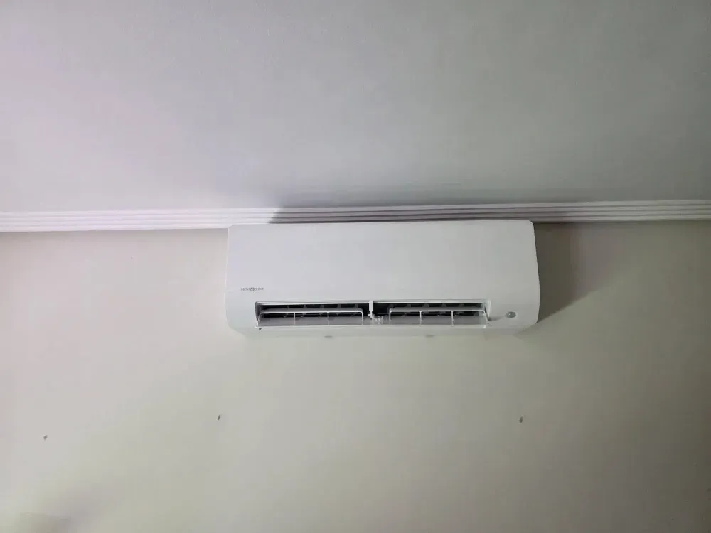 Aire acondicionado blanco de pared en una pared clara, cerca del techo