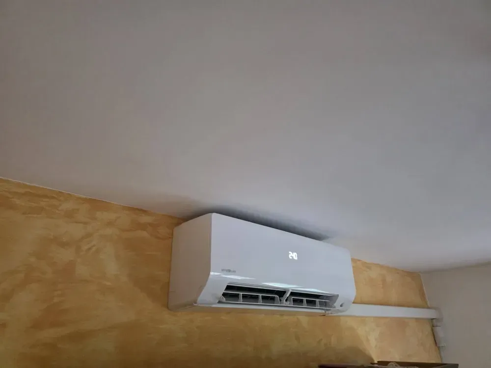 Aire acondicionado blanco de pared, cerca del techo, sobre una pared beige