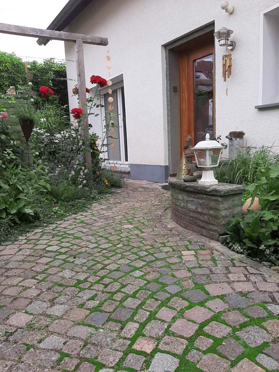 Ein Steinweg führt zu einem weißen Haus mit einer Holztür - Traumgärten Benjamin Biermeyer aus Soest