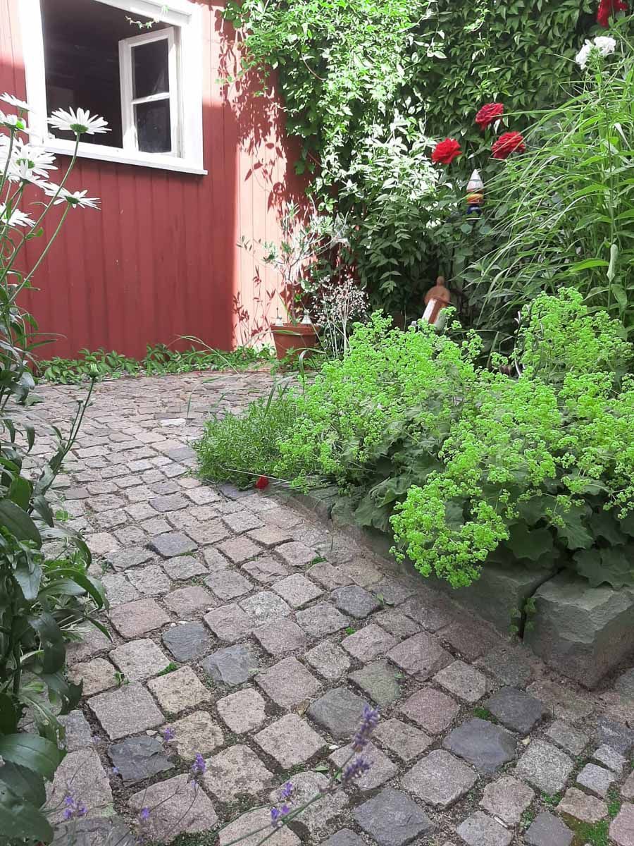 ein Steinweg führt zu einem roten Gebäude mit einem Fenster - Traumgärten Benjamin Biermeyer aus Soest