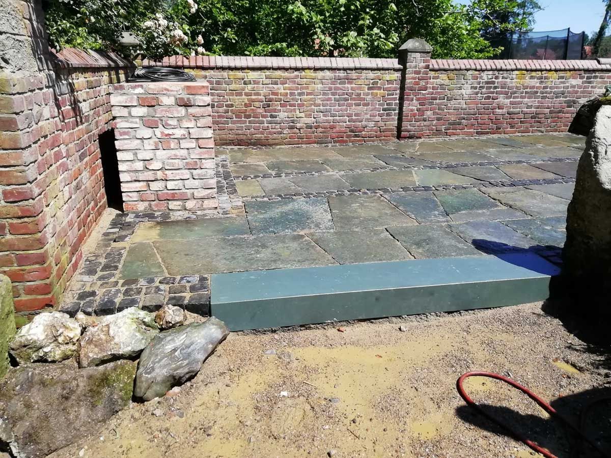 ein schwarz-weißer Hund steht auf einer Terrasse vor einer Backsteinmauer - Traumgärten Benjamin Biermeyer aus Soest