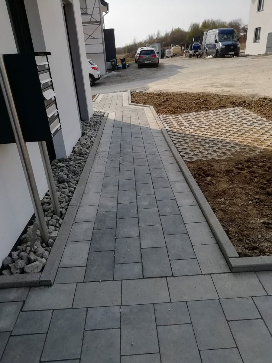 ein Gehweg , der zu einem Gebäude führt , wo Autos geparkt sind - Traumgärten Benjamin Biermeyer aus Soest