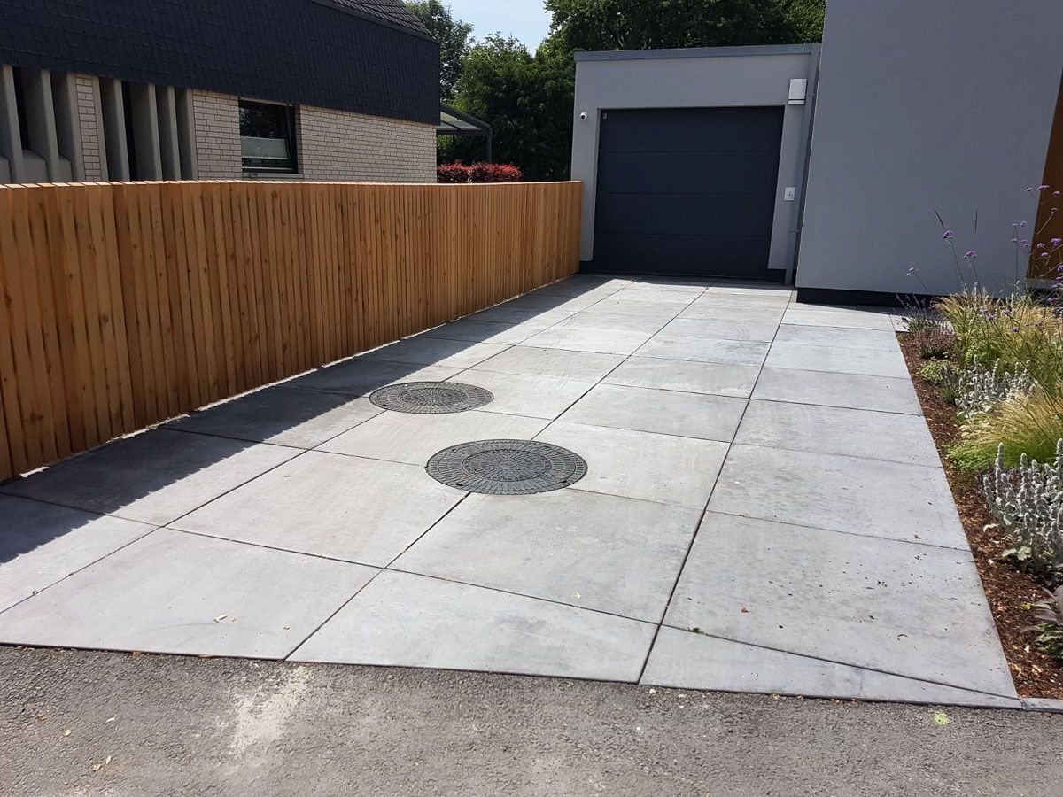 ein Betonweg mit einem Holzzaun in der Nähe eines Hauses - Traumgärten Benjamin Biermeyer aus Soest