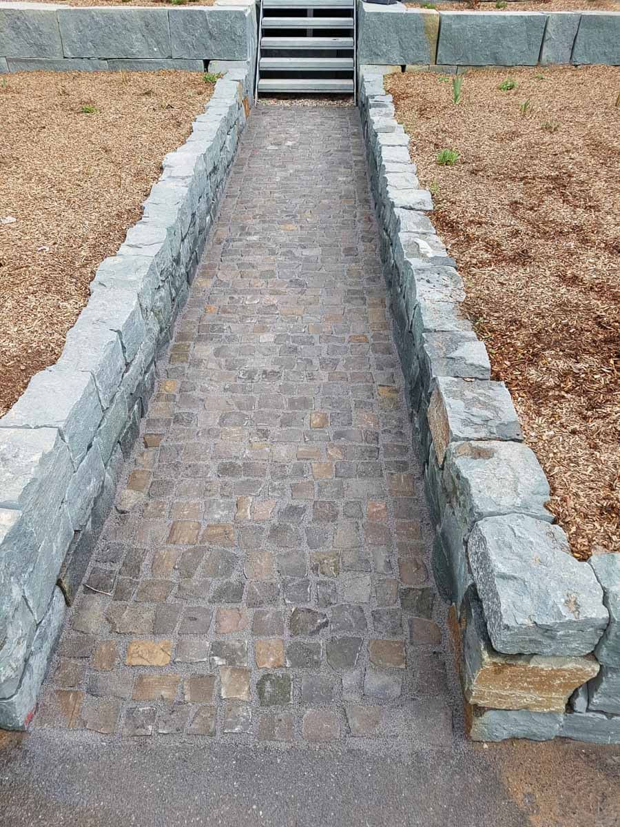 ein Gehweg , der zwischen zwei Steinmauern und einer Treppe führt - Traumgärten Benjamin Biermeyer aus Soest