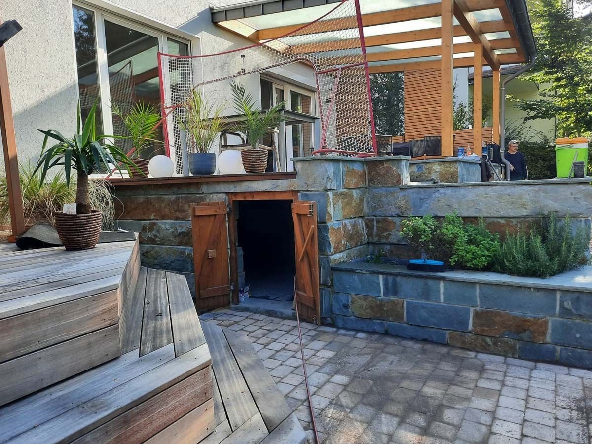 ein Haus mit einer Steinmauer und einer Holztür - Traumgärten Benjamin Biermeyer aus Soest