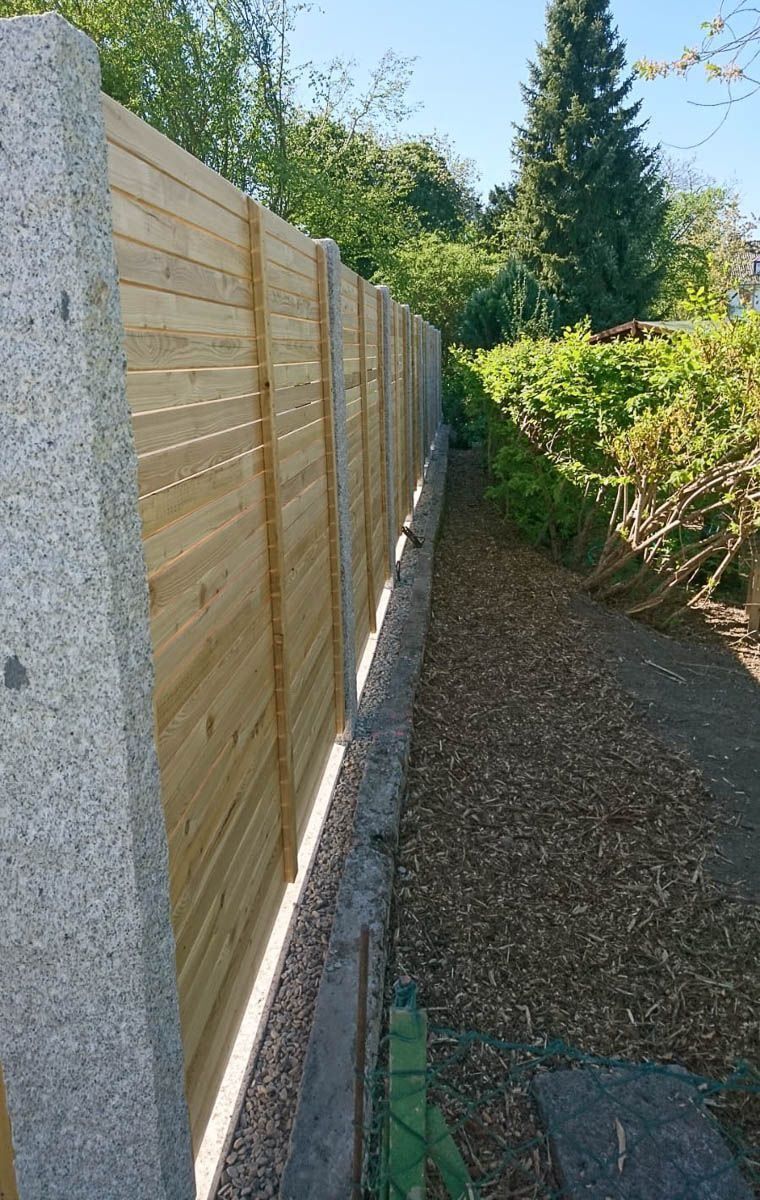 ein Holzzaun mit Steinsäulen in einem Garten - Traumgärten Benjamin Biermeyer aus Soest