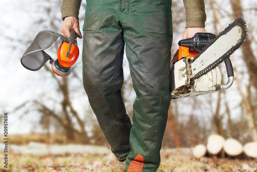 Ein Holzfäller hält eine Kettensäge und eine Schutzbrille in den Händen - Traumgärten Benjamin Biermeyer aus Soest