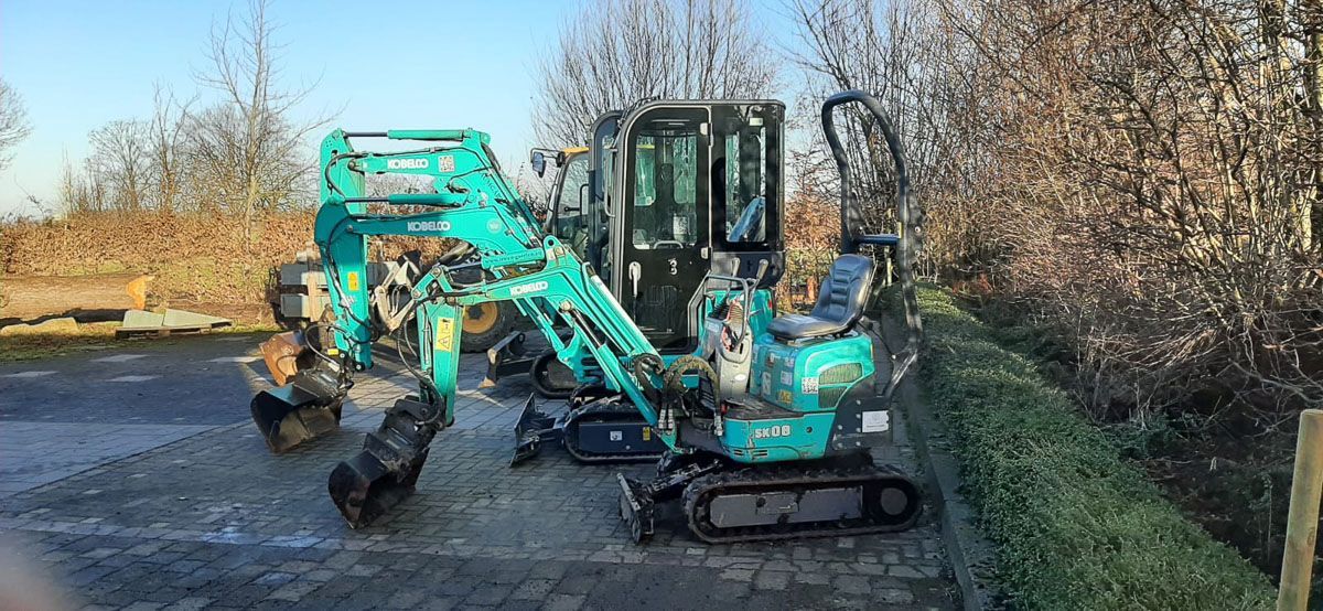 ein blauer Bagger sitzt auf einem Bürgersteig neben einem Baum - Traumgärten Benjamin Biermeyer aus Soest