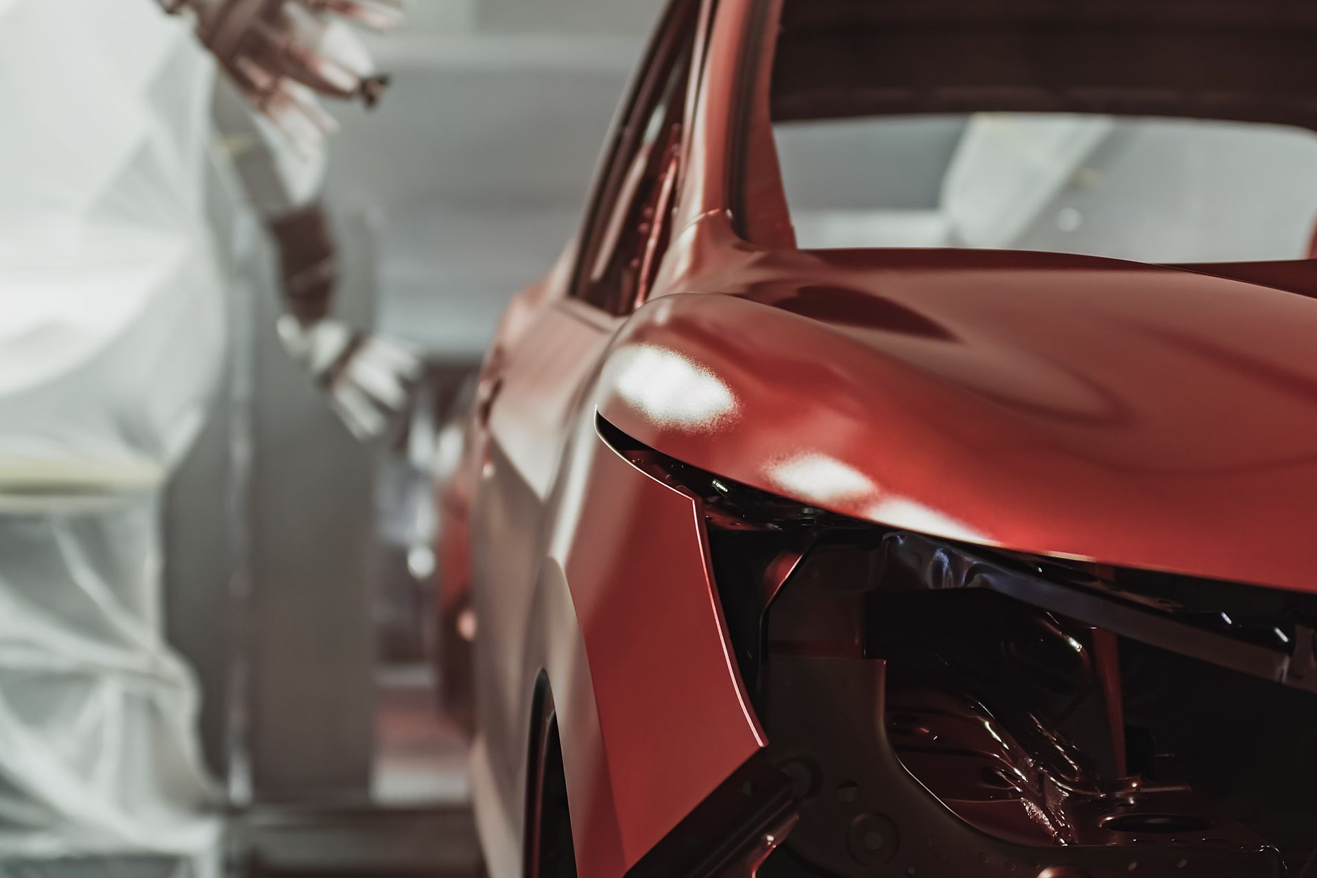 Se está pintando un coche rojo en un garaje.