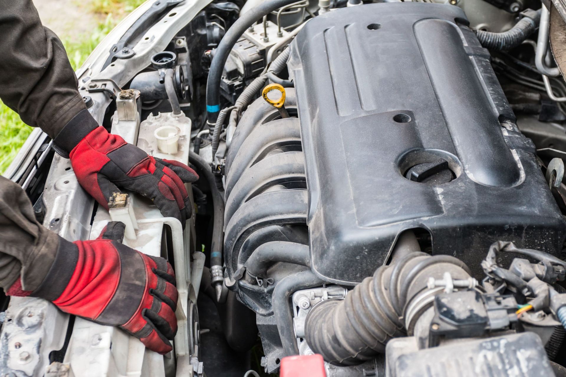 Un hombre que lleva guantes rojos está trabajando en el motor de un coche.