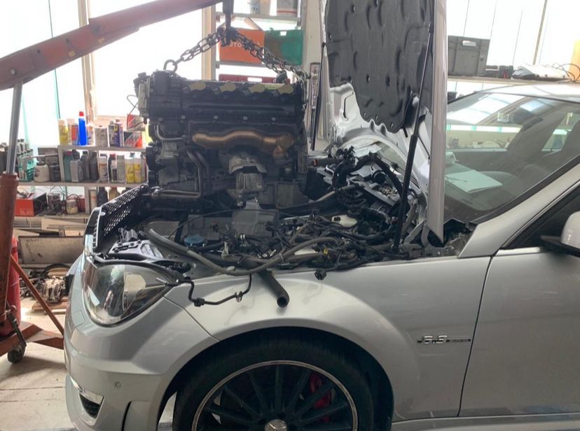 En un garaje se está trabajando en un coche con el capó abierto.