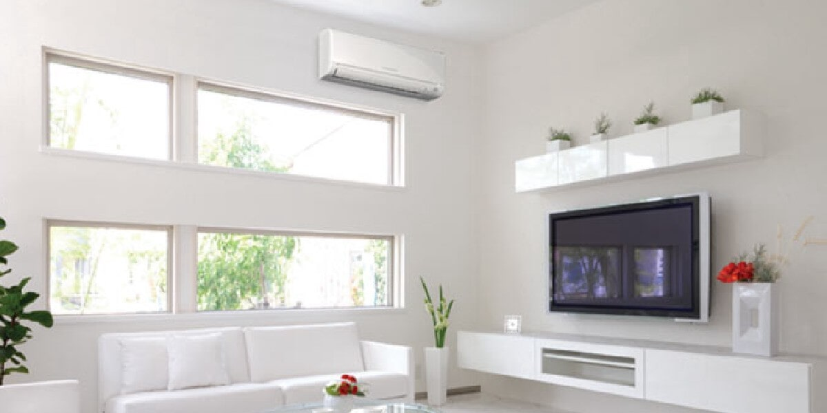 Uma sala de estar com sofá, televisão e ar condicionado.