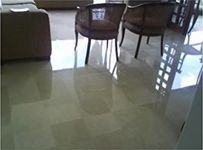 Una sala de estar con mesa y sillas y suelo de mármol.