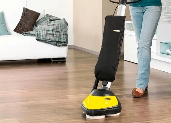 Una mujer está limpiando un piso de madera con una máquina.