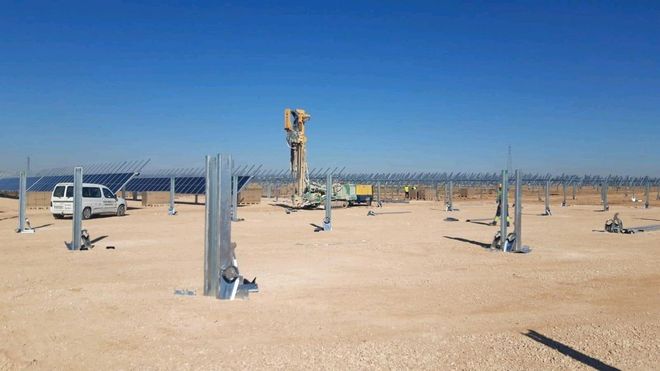 Un hombre está trabajando en una granja solar en el desierto.