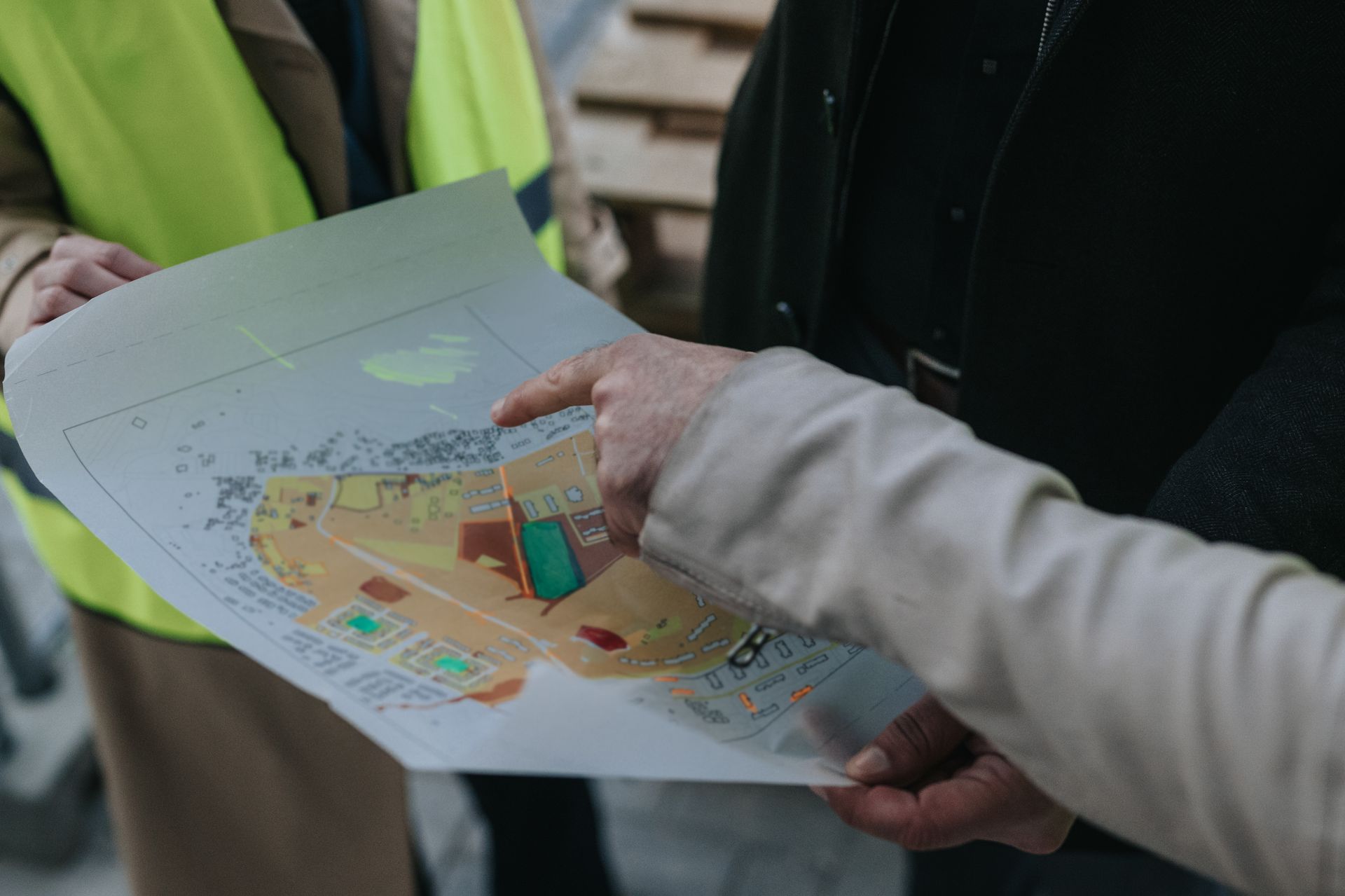 Des mains tenant un plan ou une carte colorée du site, une personne pointant du doigt une section.