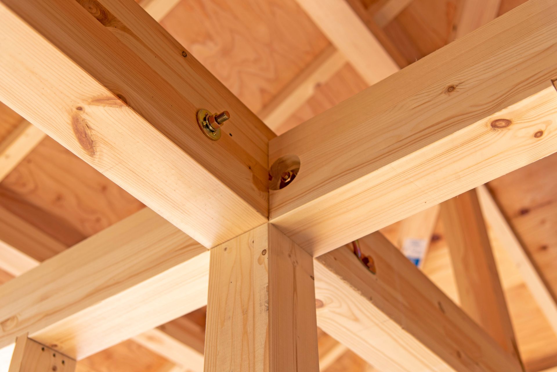 Gros plan sur des poutres de toit en bois assemblées par des fixations métalliques à une intersection de charpente en bois