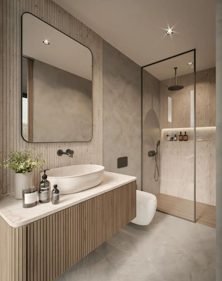 Baño moderno con tocador de madera, espejo grande, ducha de cristal y paredes grises.