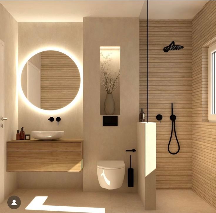 Baño moderno con tocador de madera, espejo redondo y ducha con accesorios negros.