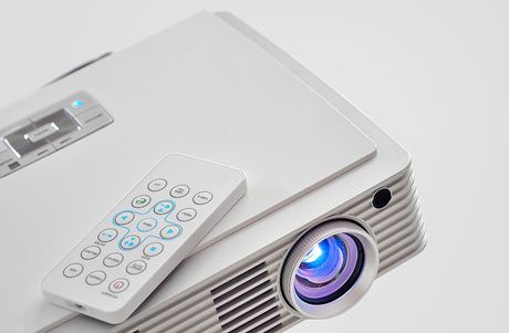 Ein weißer Projektor mit einer daran befestigten Fernbedienung.