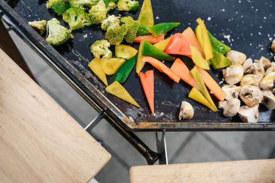 Auf einer schwarzen Grillplatte gegrilltes Gemüse: Brokkoli, Paprika (grün, gelb, orange), Pilze.