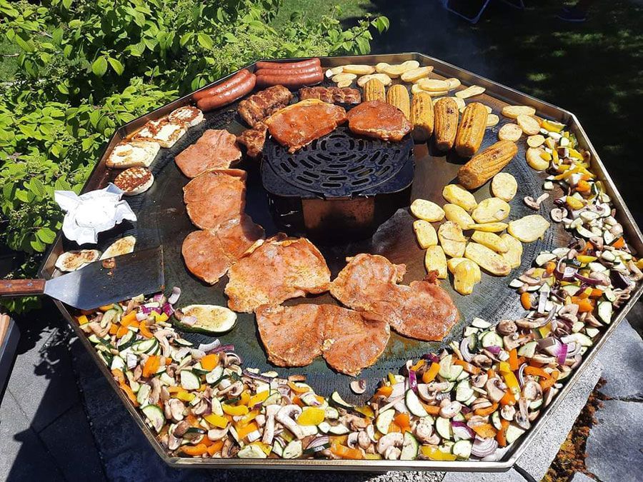 Bratpfanne mit Fleisch, Gemüse und Mais, die im Freien kochen. Verschiedene Farben an einem sonnigen Tag.