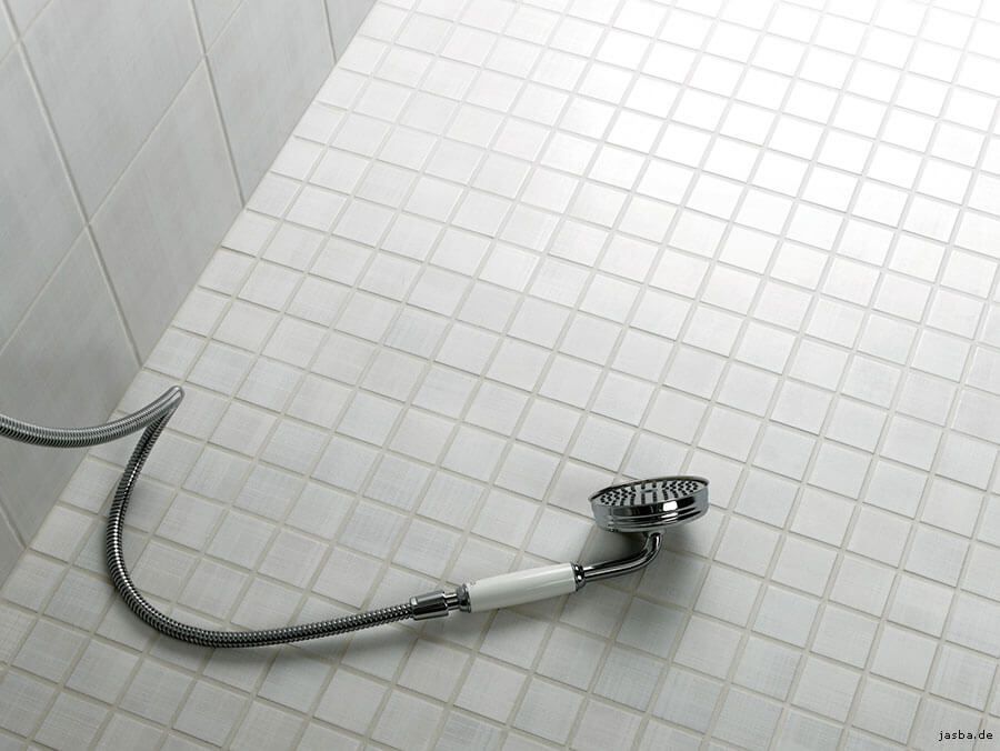 Ein Duschkopf liegt auf einem gefliesten Boden in einem Badezimmer.