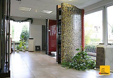 Ein Raum mit einer gefliesten Wand und einer Toilette darin.