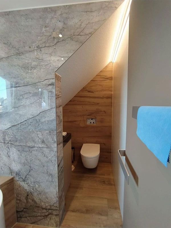 Ein Badezimmer mit Toilette und Waschbecken unter einer Treppe.