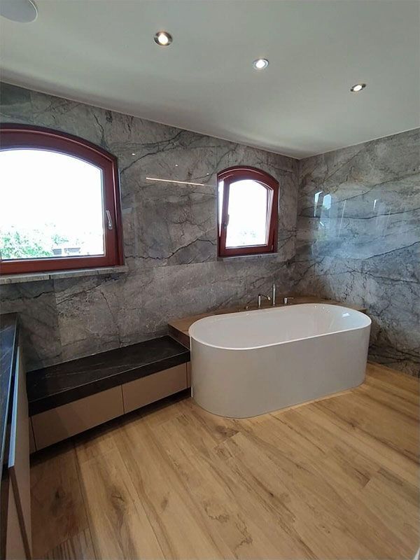 Ein Badezimmer mit Badewanne und zwei Fenstern.