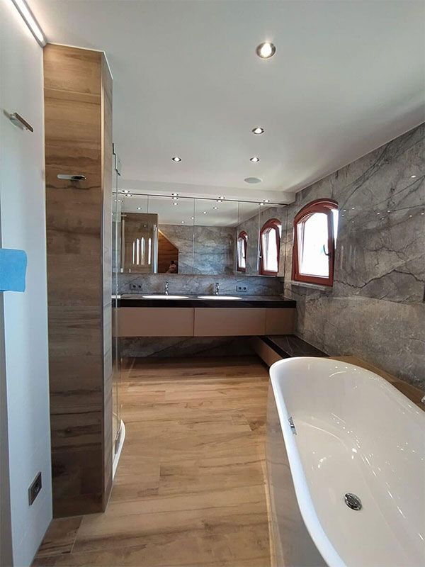 Ein Badezimmer mit Badewanne, Waschbecken und Spiegeln.