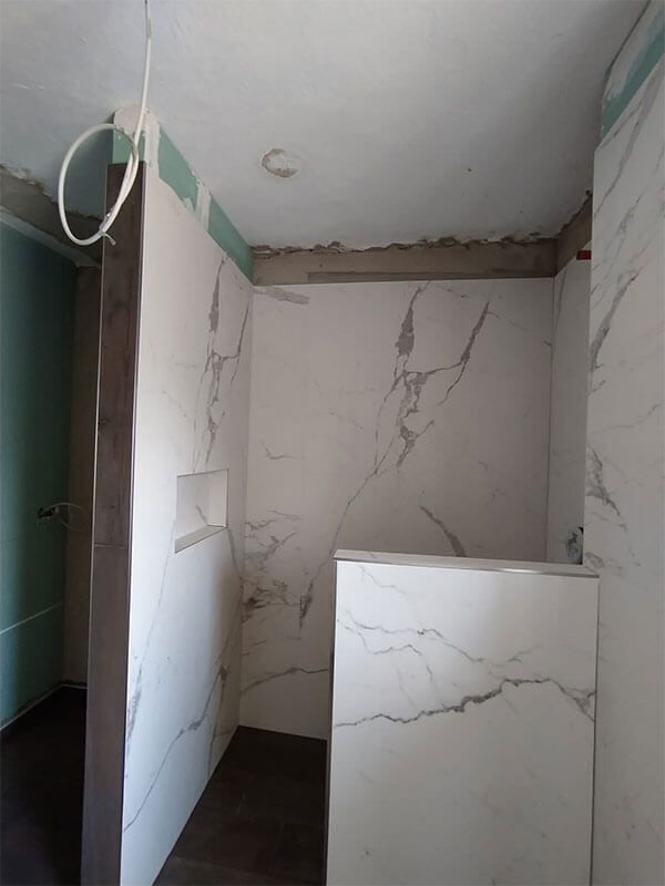 Ein im Bau befindliches Badezimmer mit Marmorfliesen an den Wänden und auf dem Boden.