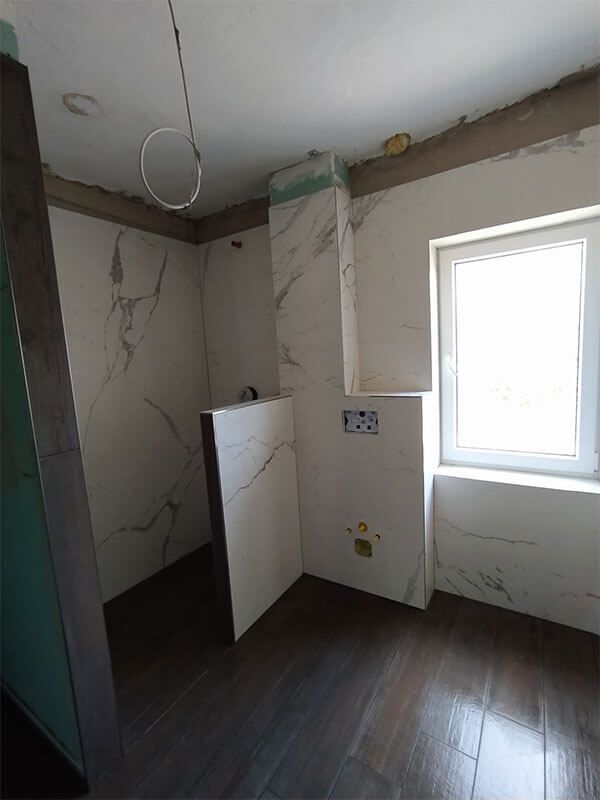 Ein im Bau befindliches Badezimmer mit Marmorfliesen und einem Fenster.