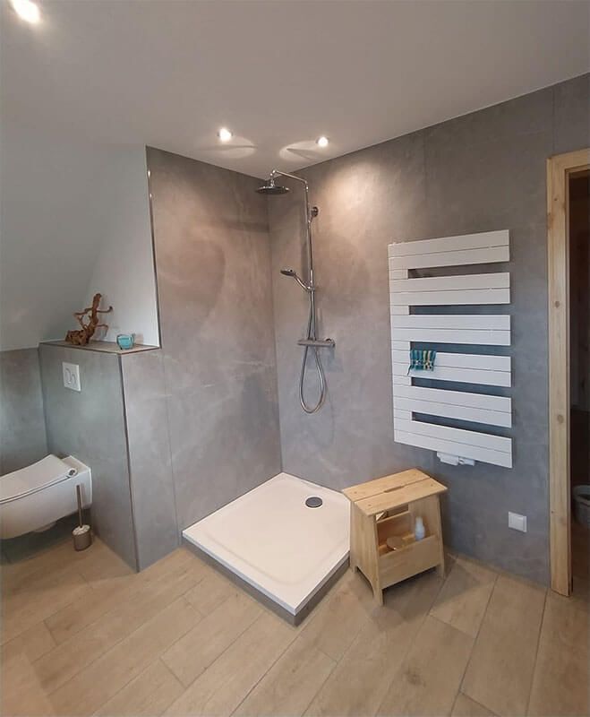 Ein Badezimmer mit ebenerdiger Dusche, Toilette und Handtuchhalter.