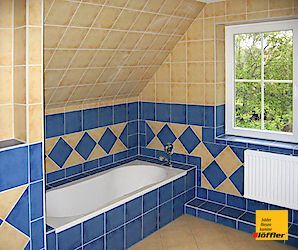 Ein Badezimmer mit blauen und gelben Fliesen und einem Fenster