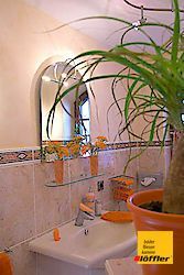 Ein Badezimmer mit Waschbecken, Spiegel und Topfpflanze.