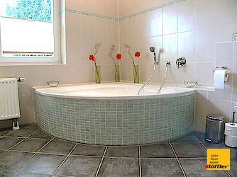 Ein Badezimmer mit Eckbadewanne und Fenster.