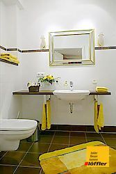 Ein Badezimmer mit Toilette, Waschbecken, Spiegel und gelben Handtüchern.