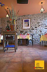 Ein Restaurant mit Tischen und Stühlen und einer Steinmauer.