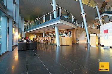 Eine große Lobby eines Gebäudes mit einer Bar und einem Balkon.